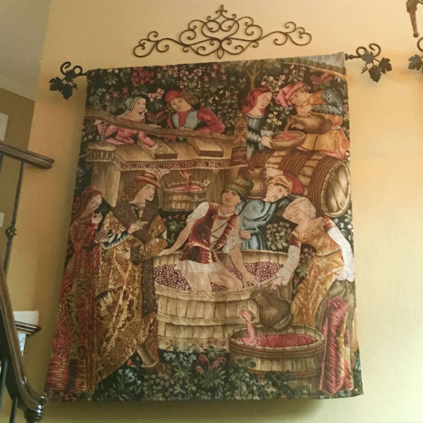 Pressing the Grapes tapestry hanging in a home